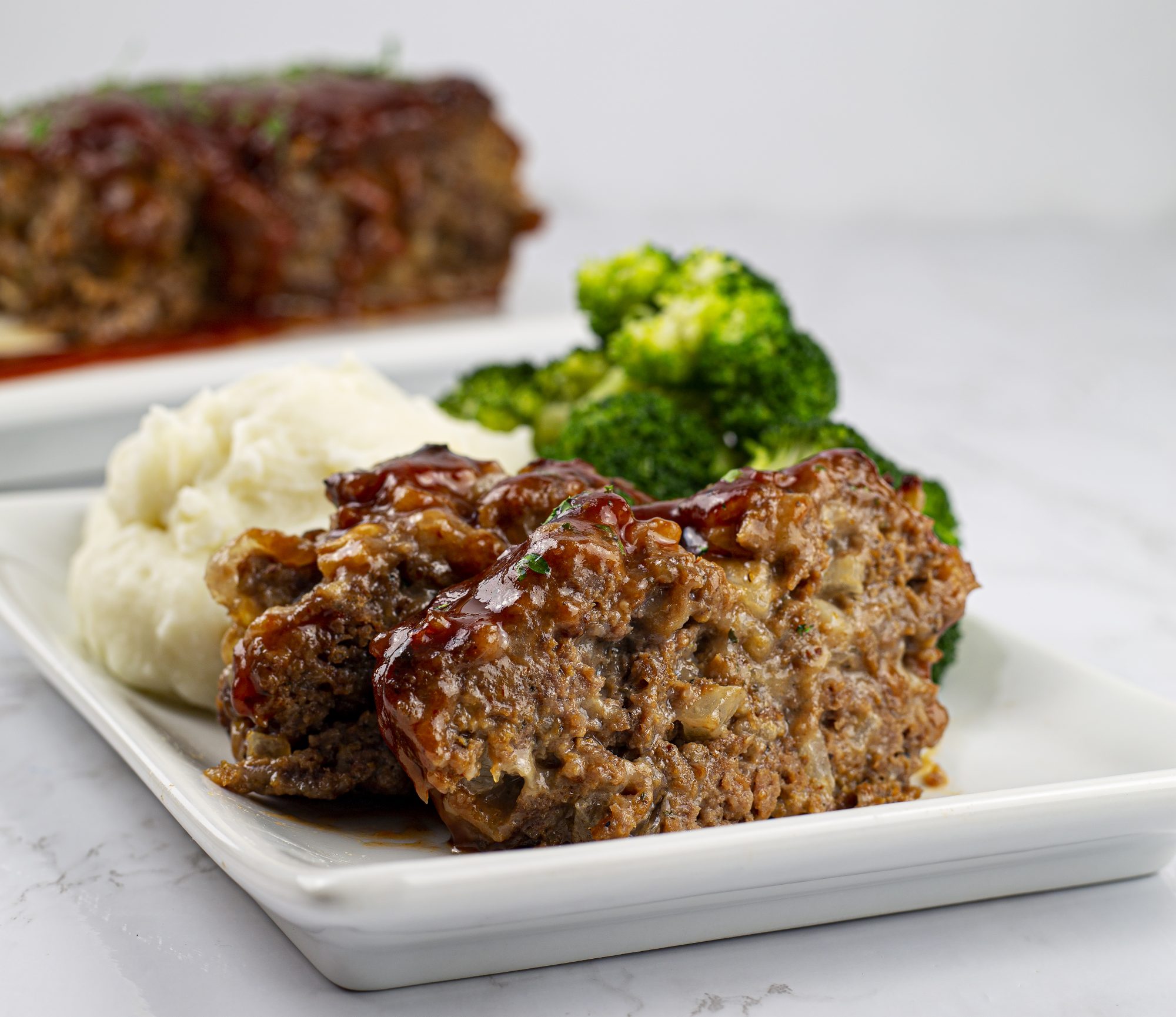 Meatloaf on a plate with broccoli and mashed potatoes