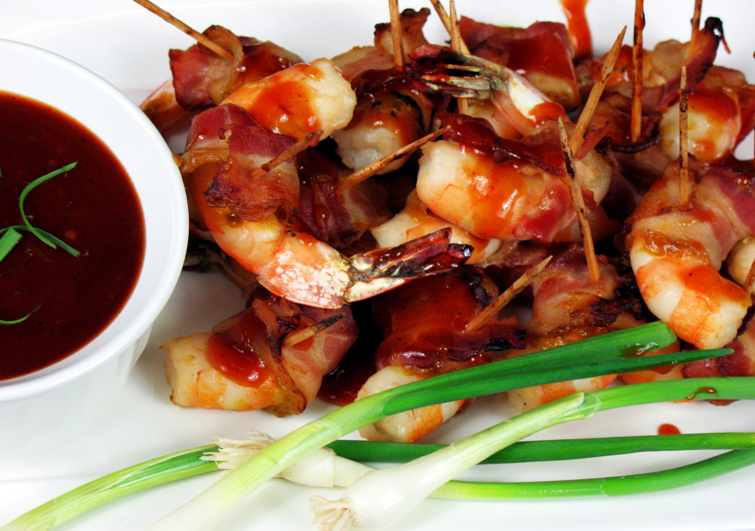 Bacon wrapped shrimp with a cup of sauce