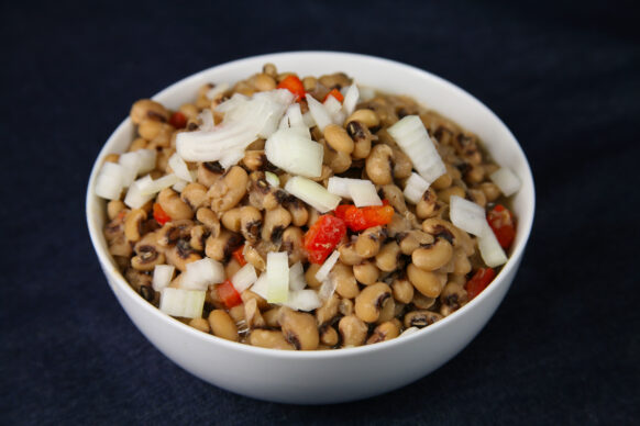 Black eyed peas in a bowl topped with onions and peppers